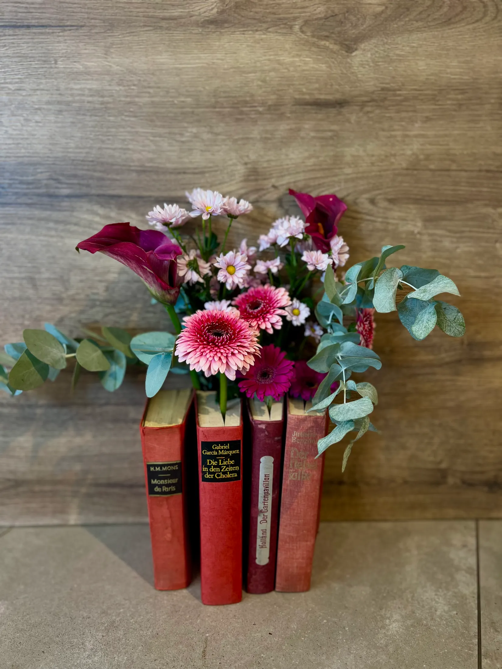 Blumenarrangement zwischen alten Buchrücken