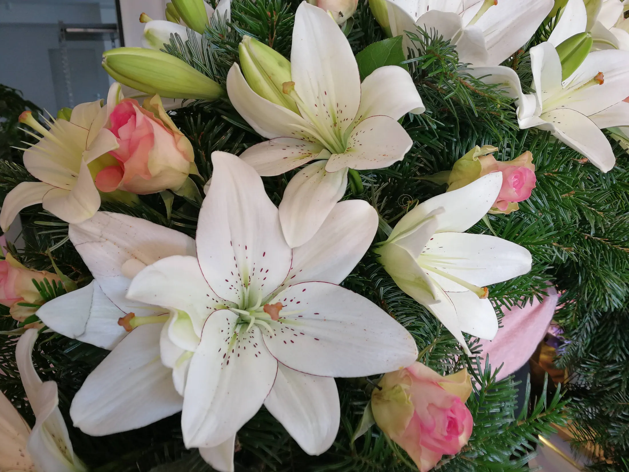Weiße Lilien und zartrosa Rosen in einem Gesteck