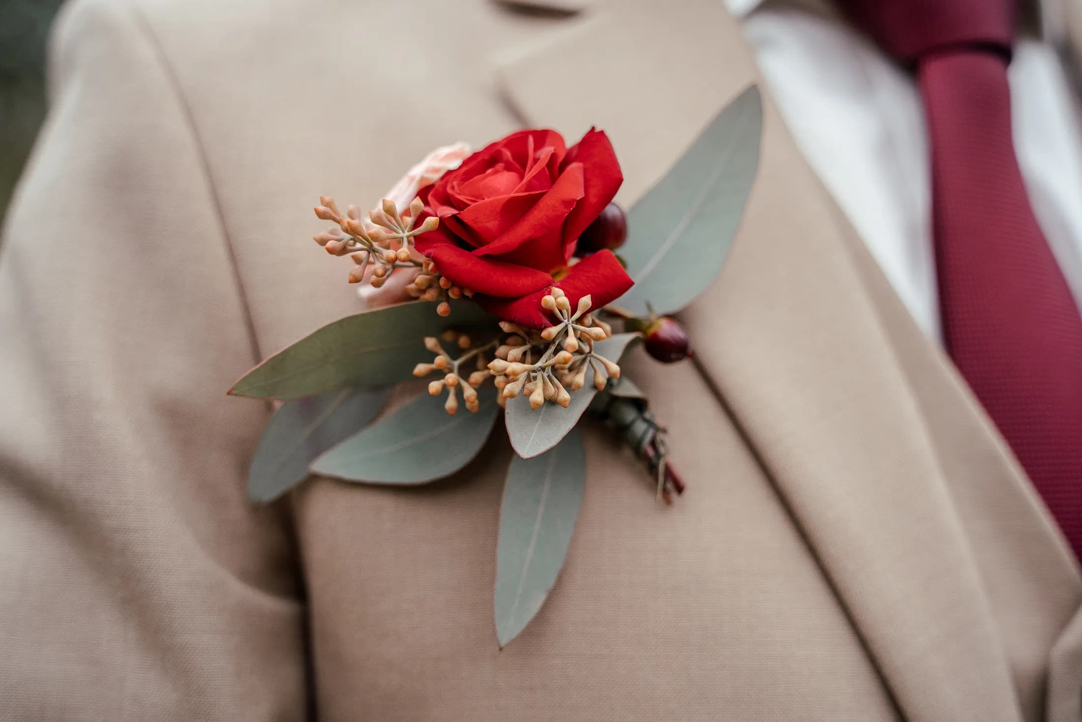 Anstecker mit roter Rose am Sakko des Bräutigams