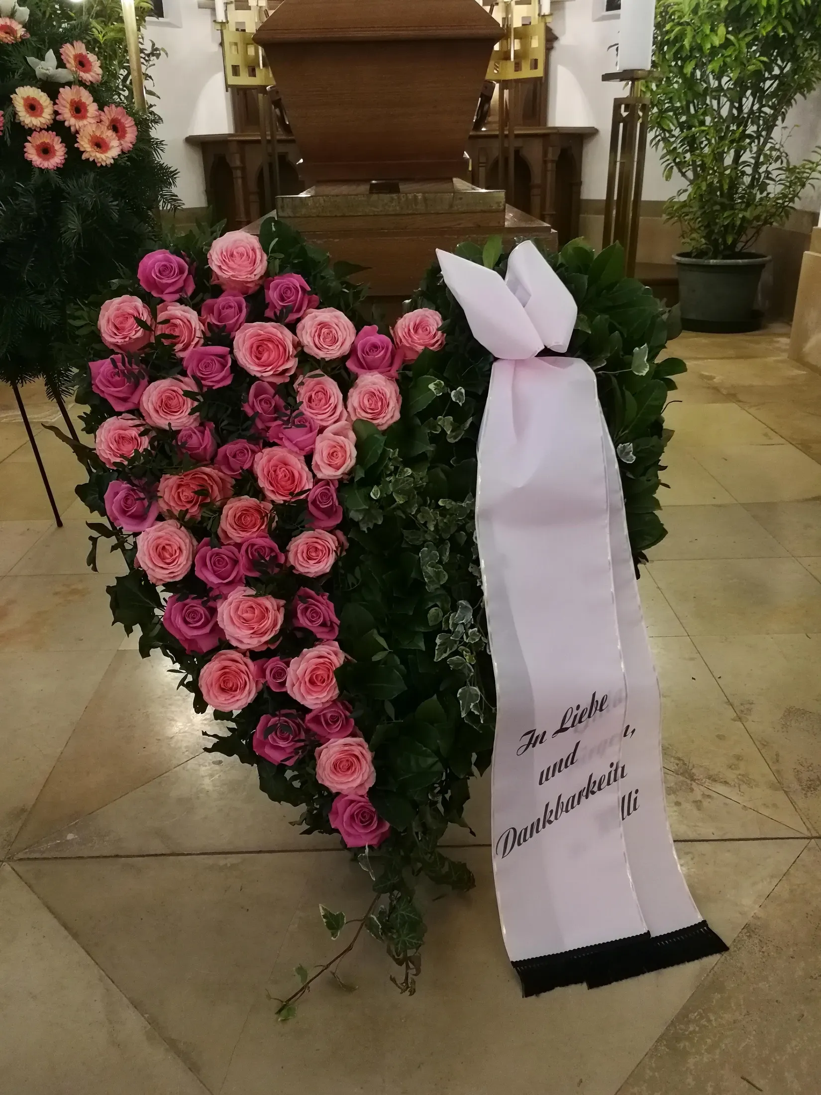 Trauerherz aus rosa Rosen mit beschrifteter Schleife