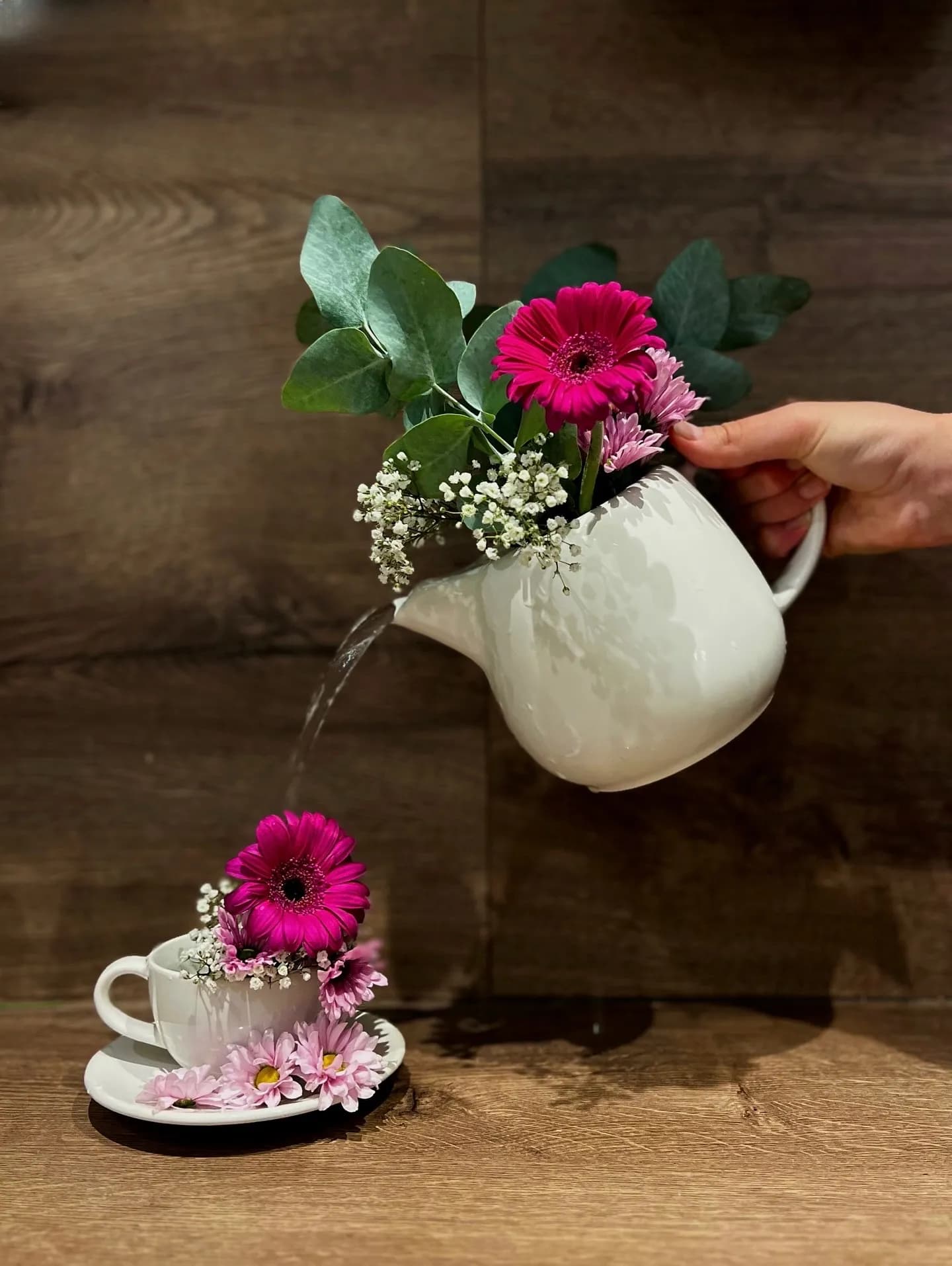 Bepflanzte Kanne und Tasse mit Gerbera als Tischdekoration