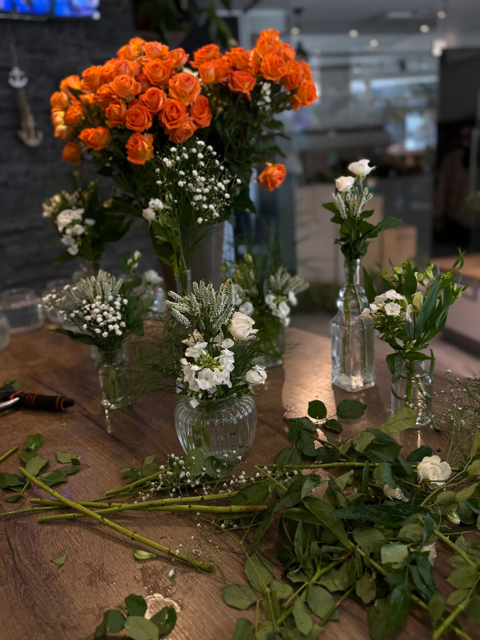 Werkbank im Geschäft mit orangen Rosen und kleinen Vasen