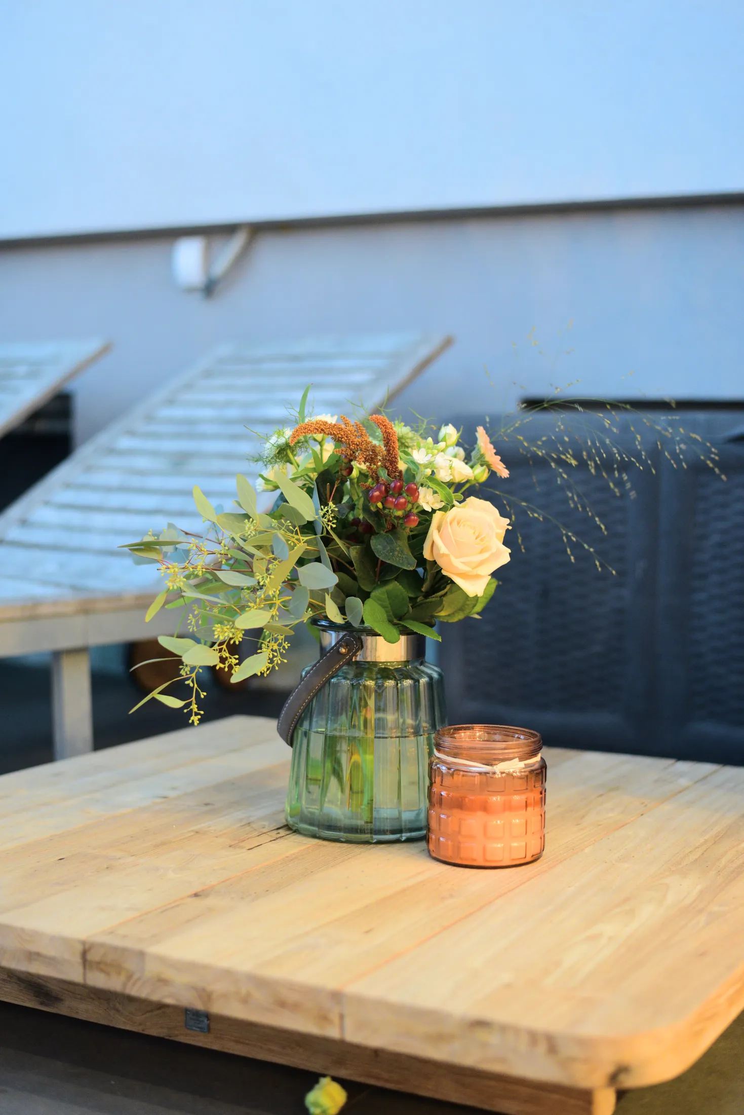 Bepflanzte Vase mit Rosen und Eukalyptus auf einem Terrassentisch