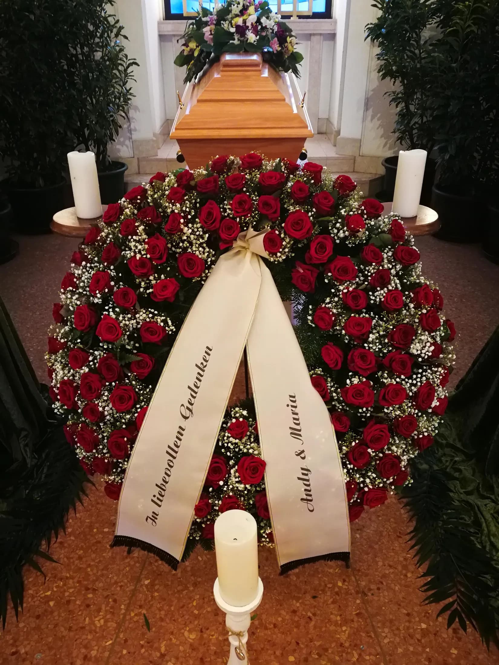 Trauerkranz aus roten Rosen mit beschrifteter Schleife